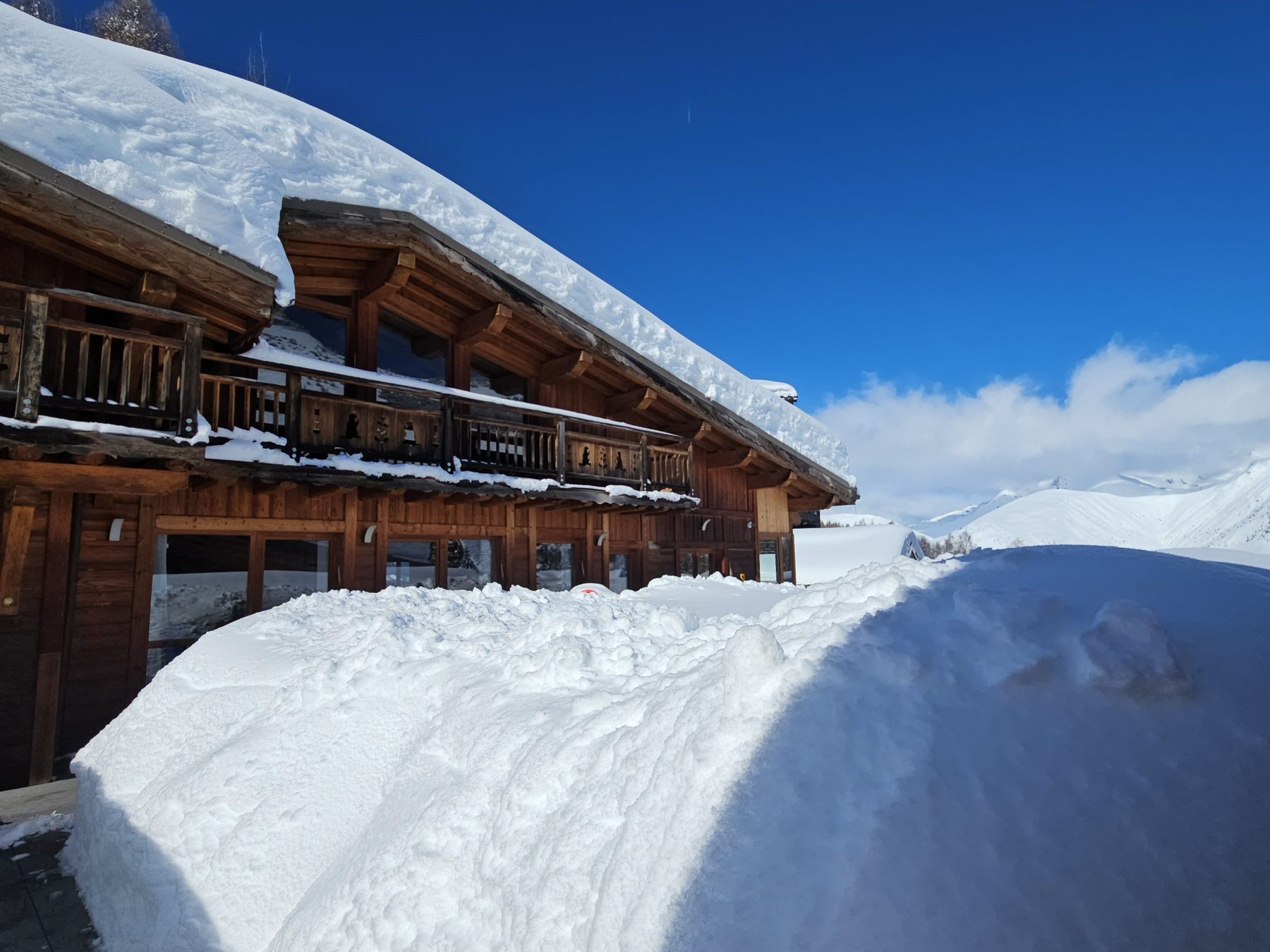 Our chalet in Les Deux Alpes under a blue sky, carved balconies and deep snow